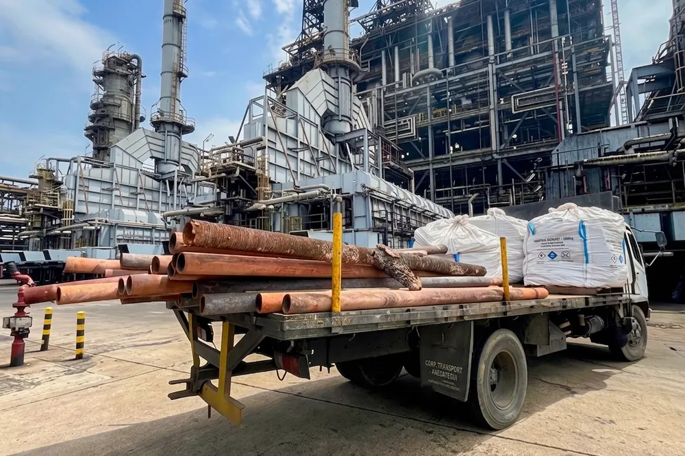 Camión plataforma con tubería y materiales dentro de la refinería