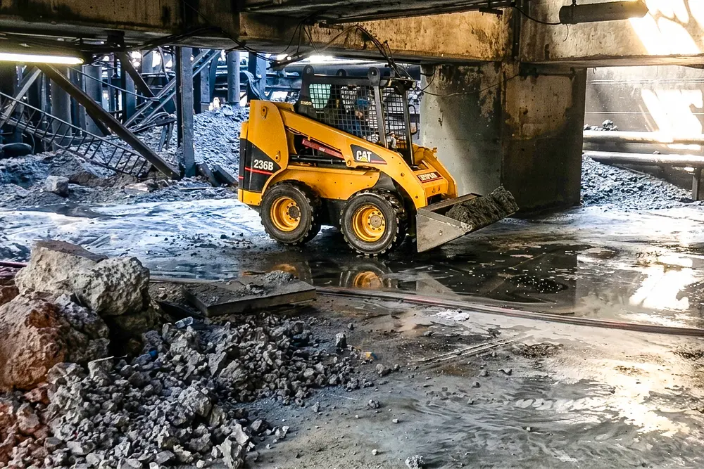 Minicargadora trabajando en la limpieza de un área con residuos