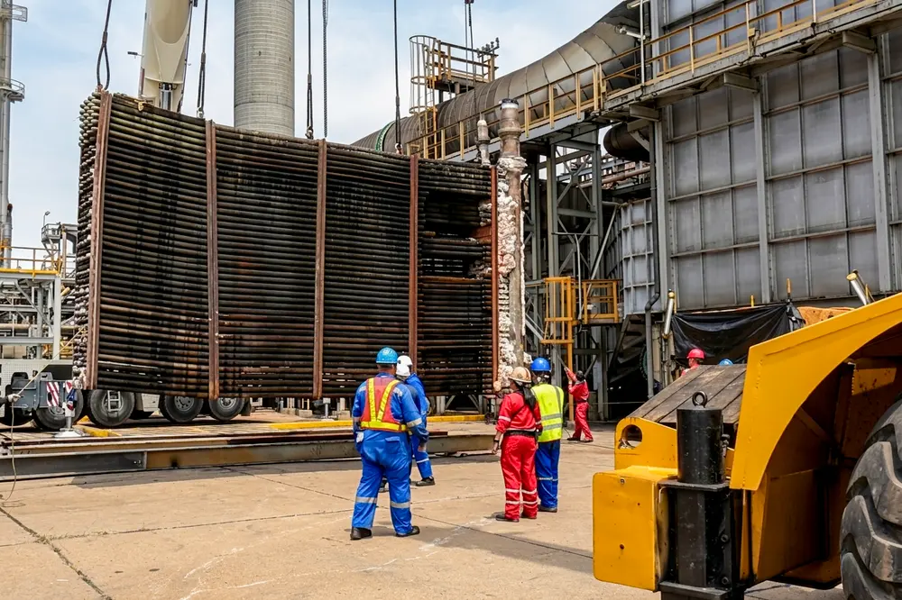 Cuadrilla dirigiendo la maniobra de un haz de tubos a pie de planta
