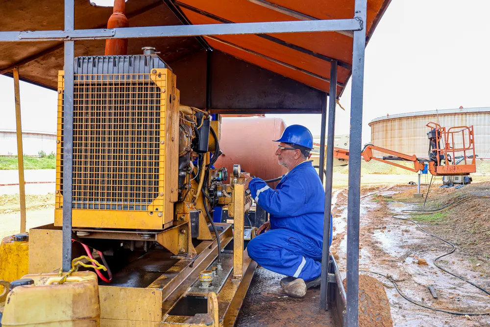 Técnico revisando un compresor bajo cobertizo en obra