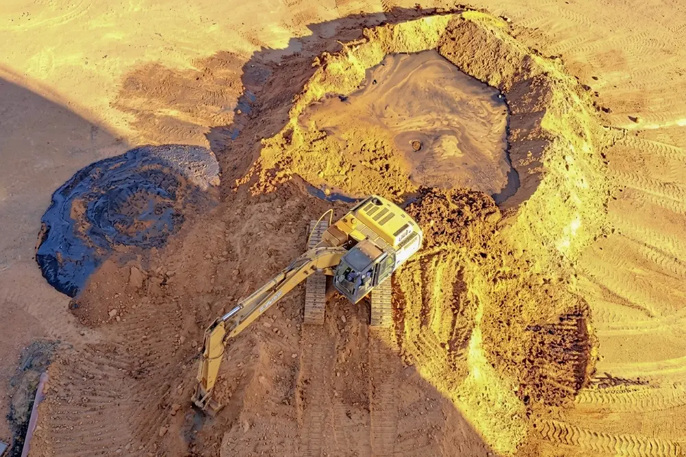 Retroexcavadora excavando el terreno con geotextil desplegado