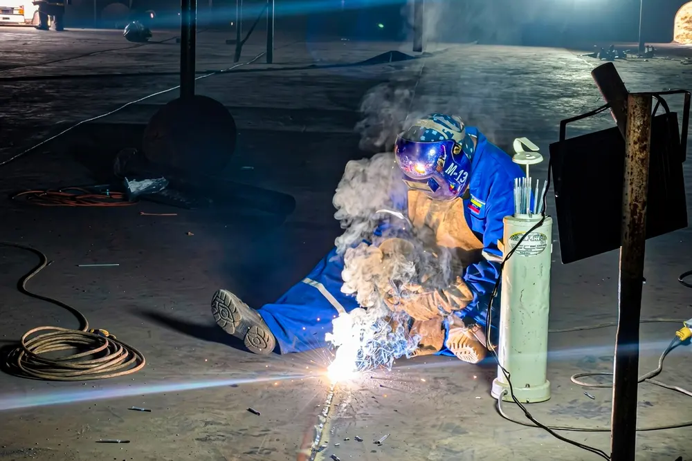 Soldador trabajando en posición bajo techo dentro del tanque